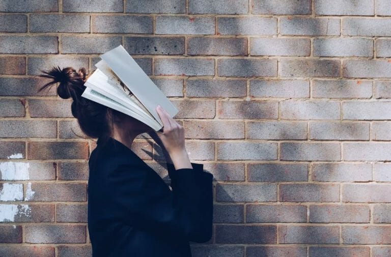 a female student holding a book over her face