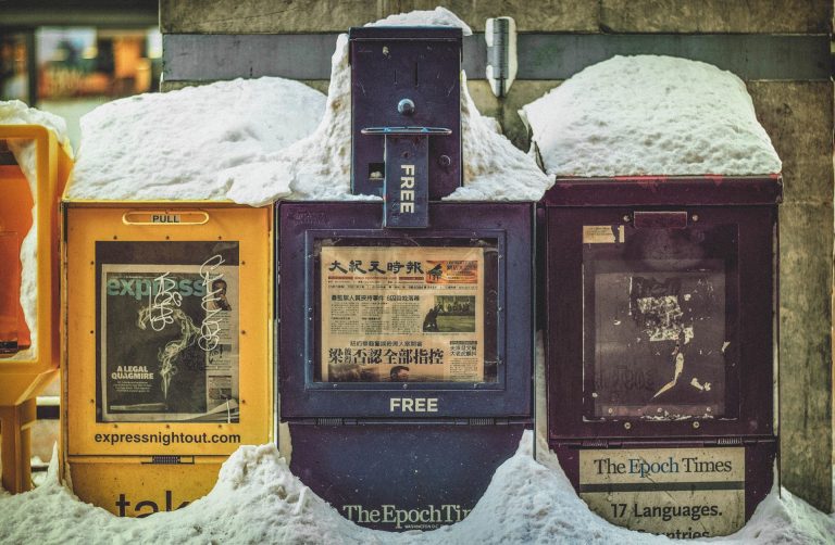 Free newspaper boxes covered in snow beneath the Chinatown Arch in downtown Washington, DC.