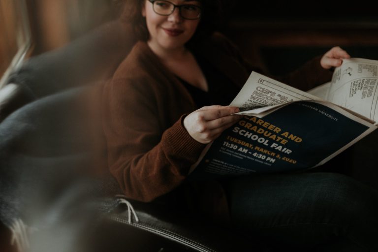 woman in brown long sleeve shirt holding newspaper